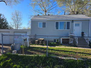 View of front of property with a fenced front yard, roof with shingles, and a garage
