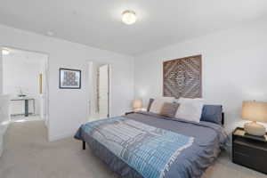 Bedroom with light carpet and en suite bath