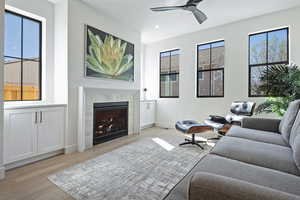 Living room with a tile fireplace, light wood-style floors, ceiling fan, recessed lighting, and healthy amount of natural light