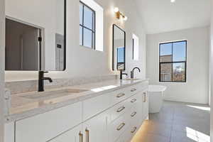 Bathroom with double vanity, a soaking tub, light tile patterned flooring, and lofted ceiling