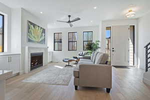 Living room featuring a fireplace, light wood-style flooring, ceiling fan, and recessed lighting