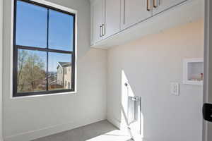 Laundry room featuring hookup for a washing machine, cabinet space, light tile patterned floors, and hookup for an electric dryer
