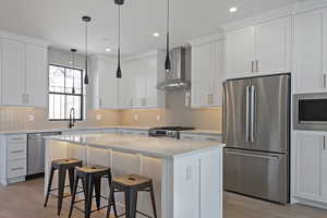 Kitchen featuring stainless steel appliances, a kitchen breakfast bar, and white cabinets