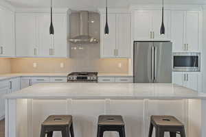 Kitchen featuring stainless steel appliances, a kitchen bar, backsplash, and white cabinets