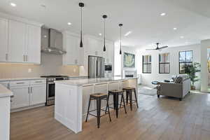 Kitchen with open floor plan, stainless steel appliances, a kitchen island, a breakfast bar, and light wood-type flooring
