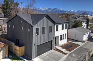 Modern inspired farmhouse with roof with shingles, board and batten siding, an attached garage, a mountain view, and driveway