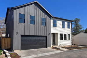 View of front of property featuring board and batten siding, an attached garage, and driveway
