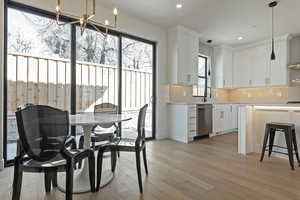 Kitchen featuring white cabinets, hanging lights, light wood-type flooring, a breakfast bar, and stainless steel dishwasher