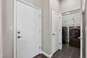Laundry room featuring washer and dryer and dark tile patterned flooring