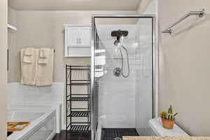 Bathroom with a garden tub, a stall shower, and tile walls