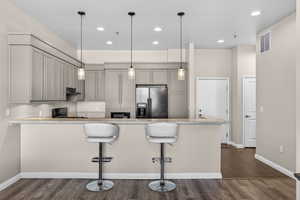 Kitchen with a peninsula, black appliances, light stone countertops, and dark wood-style flooring