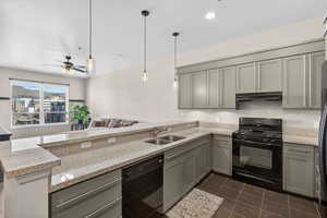 Kitchen with black appliances, gray cabinetry, light stone countertops, and a peninsula