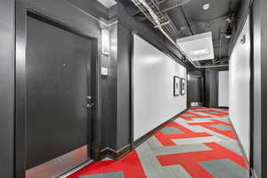 Hall featuring dark carpet and baseboards