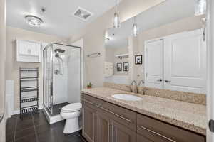 Full bathroom featuring a shower stall, dark tile patterned floors, and vanity