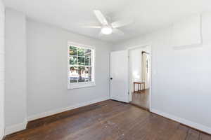 Empty room with dark wood-type flooring and a ceiling fan