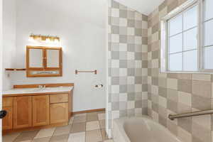 Bathroom with vanity, a bath, and light tile patterned floors