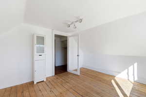 Unfurnished bedroom with vaulted ceiling and light wood-style floors