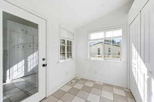 Doorway to outside featuring lofted ceiling and tile patterned floors