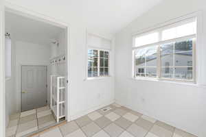 Spare room featuring lofted ceiling and light tile patterned floors
