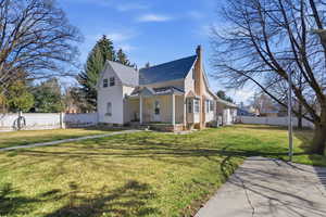 View of front of property featuring a porch, a chimney, and a shingled roof