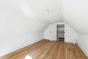 Additional living space featuring light wood-style floors and vaulted ceiling