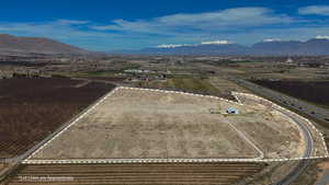 Aerial view of sparsely populated area with large plots for crops and a mountain backdrop