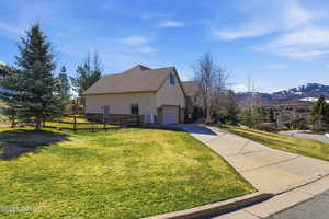 View of side of property featuring stone siding, concrete driveway, a garage, stucco siding, and a mountain view