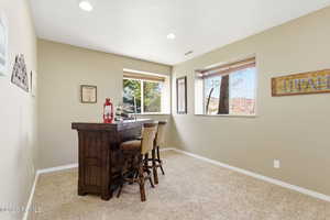 Indoor dry bar with light carpet and recessed lighting