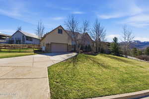 View of front of property with driveway, a garage, stone siding, and stucco siding