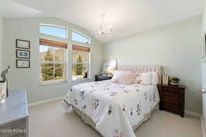Bedroom with lofted ceiling, a chandelier, and light carpet