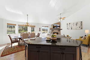 Kitchen featuring a fireplace, a center island, light wood-style flooring, open floor plan, and lofted ceiling