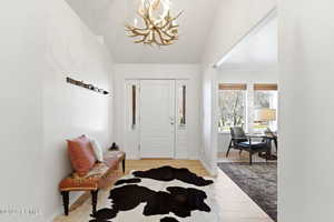 Entryway with light wood-type flooring, suspended lighting, and vaulted ceiling