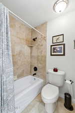 Bathroom with a textured ceiling, shower / bathtub combination with curtain, and tile patterned floors