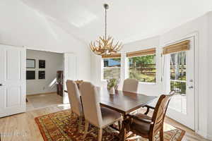 Dining area with a chandelier, light wood-style flooring, lofted ceiling, healthy amount of natural light, and washer and clothes dryer