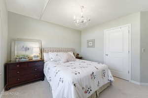 Bedroom featuring light colored carpet and a chandelier