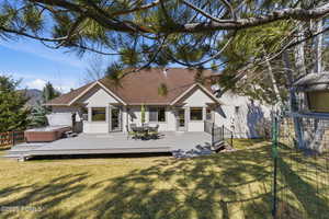 Back of property with a hot tub, stucco siding, outdoor dining space, a wooden deck, and a shingled roof