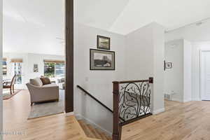 Hallway featuring an upstairs landing, light wood-style floors, and lofted ceiling