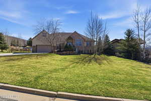 View of front of property featuring driveway, a front lawn, an attached garage, and brick siding