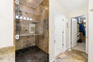 Bathroom featuring a stall shower, stone finish floors, and a spacious closet