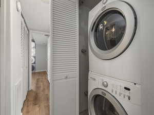 Laundry area featuring wood finished floors and stacked washer and clothes dryer