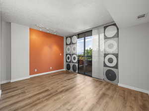 Empty room with floor to ceiling windows, rail lighting, and wood finished floors