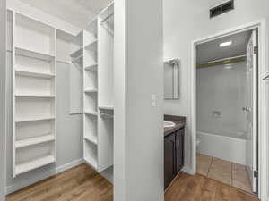 Walk in closet with light wood finished floors