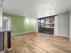 Unfurnished room with rail lighting, expansive windows, light wood-style floors, and a textured ceiling