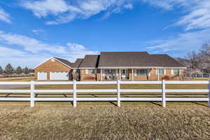 View of front facade featuring a fenced front yard, brick siding, concrete driveway, a garage, and a shingled roof