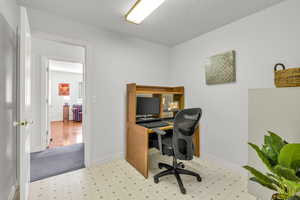 Office area featuring light flooring and a textured ceiling