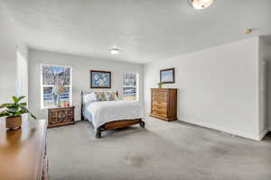 Bedroom with a textured ceiling and light colored carpet