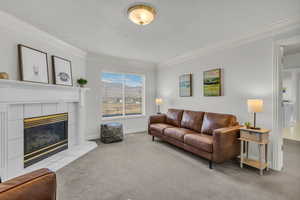Living area featuring crown molding, light carpet, a tile fireplace, and a textured ceiling
