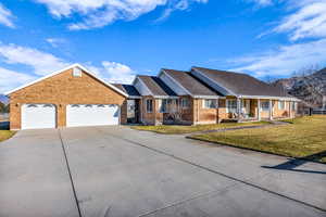 Ranch-style house featuring a front lawn, concrete driveway, a garage, covered porch, and brick siding