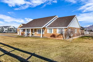 View of front of property with covered porch, roof with shingles, and brick siding