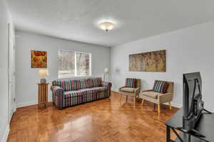 Living room featuring a textured ceiling and parquet flooring